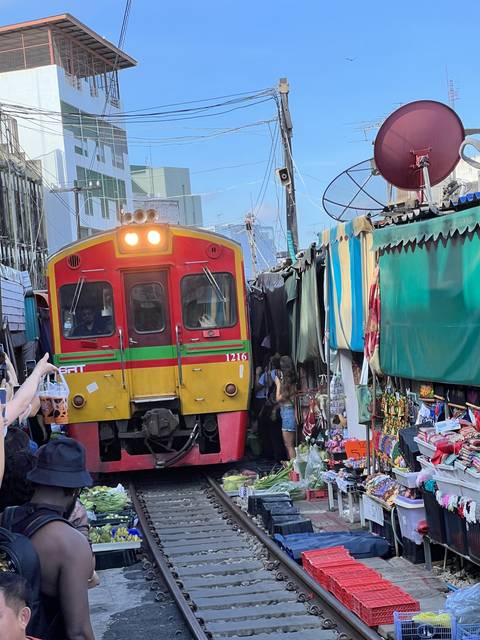 A market with a train passing through a narrow street.