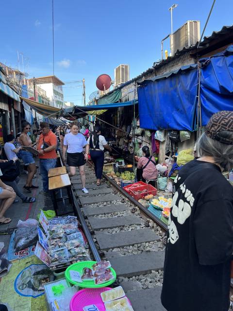       A busy railway market with people and goods on either side.
  