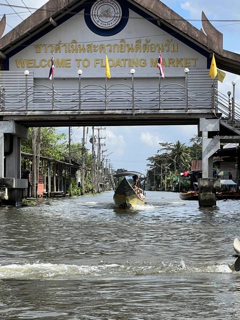 Boat approaching a market sign at a floating market.