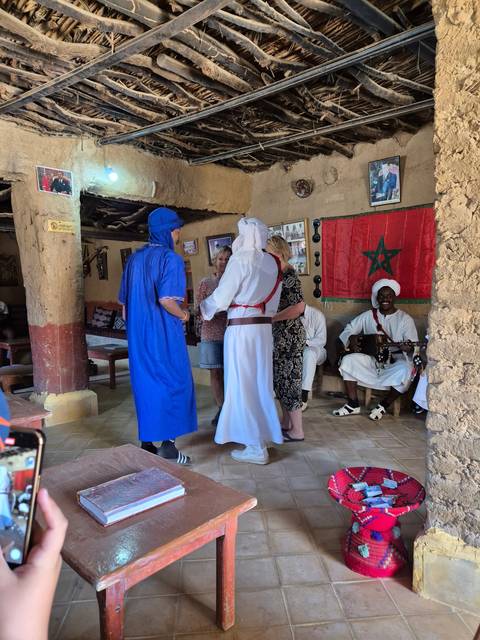       People in traditional attire inside a rustic setting.
  
