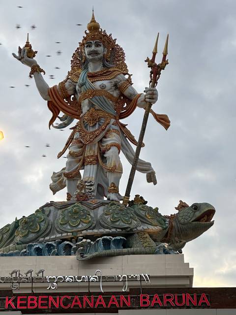 A large sculpture featuring a mythological figure and text underneath.