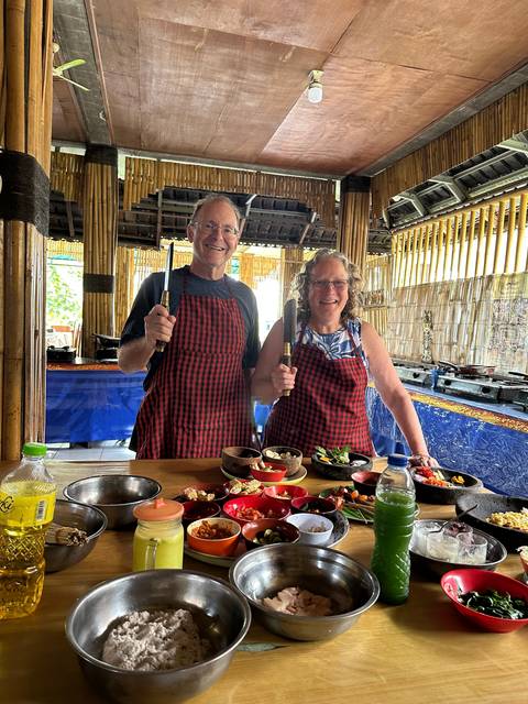       Two people cooking with various ingredients.
  
