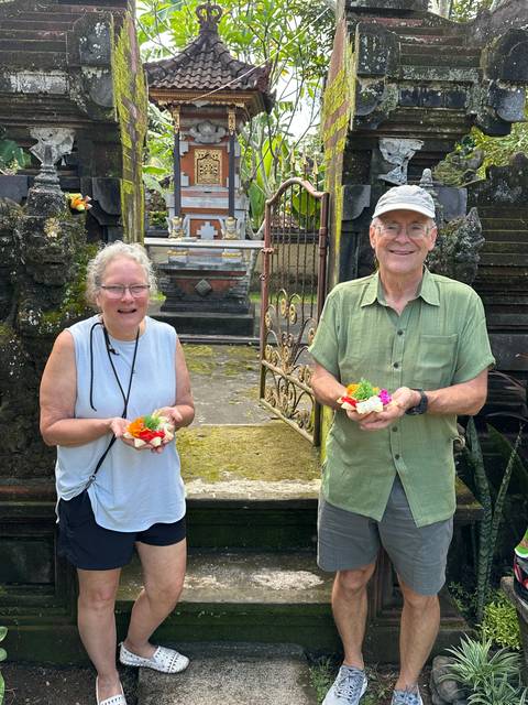Two people holding colorful offerings in a temple.