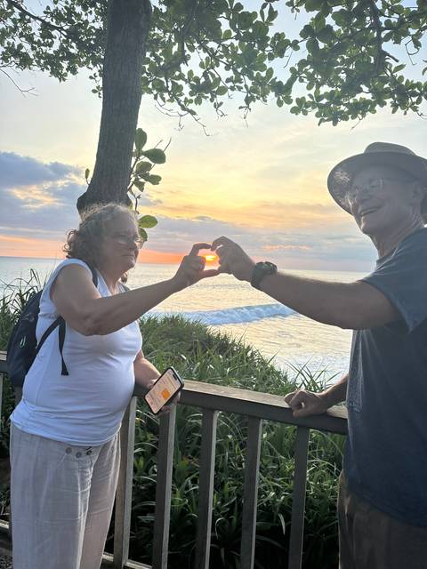       People taking photos of the sunset by the ocean.
  