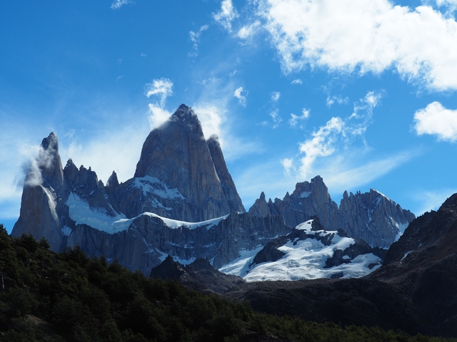       Majestic mountain peaks with snow under a blue sky.
  