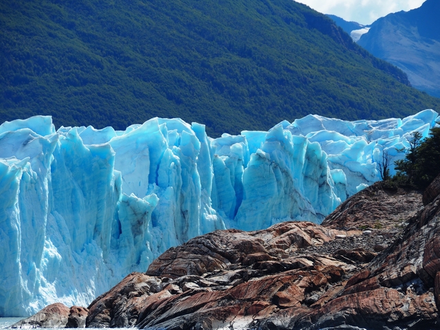      Close-up of vibrant blue glacier ice with rocky foreground.
  
