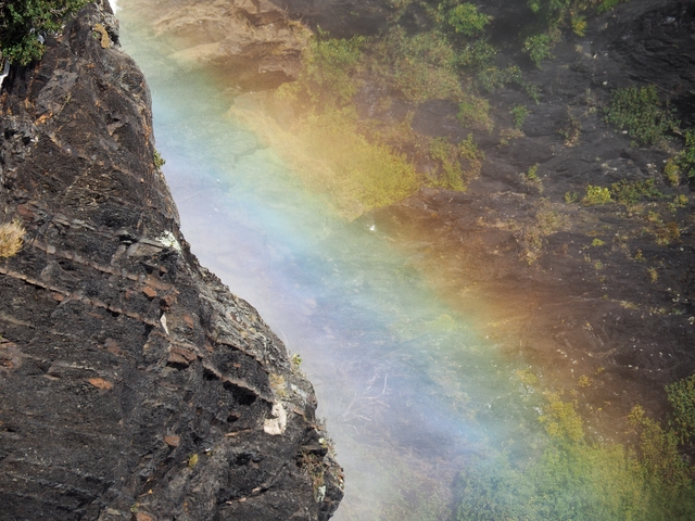       A rock wall with a rainbow arcing across the mist.
  