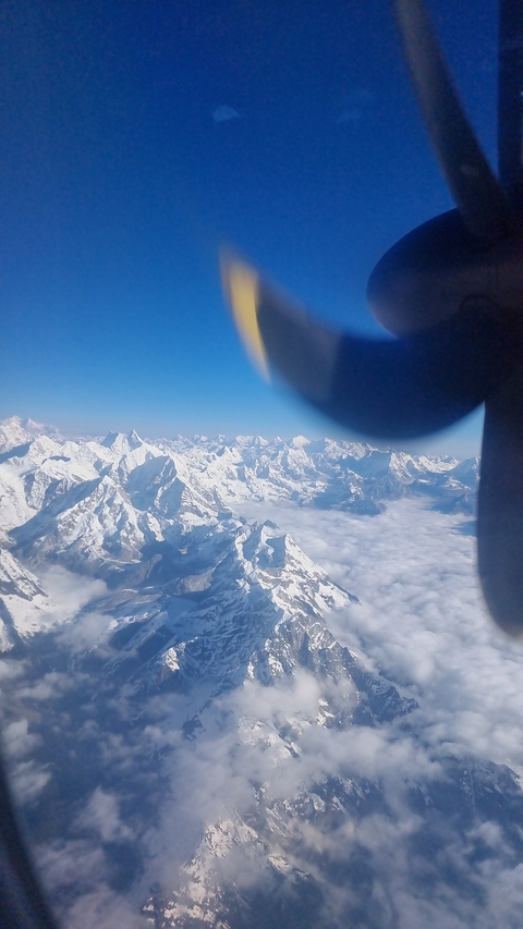 Aerial view of snow-covered mountains with propeller in view.