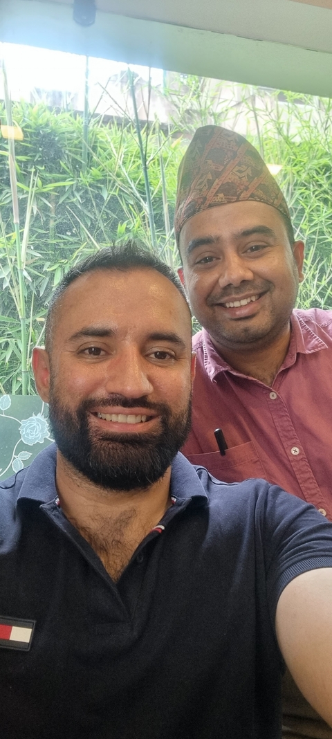 Two men smiling with a natural backdrop.