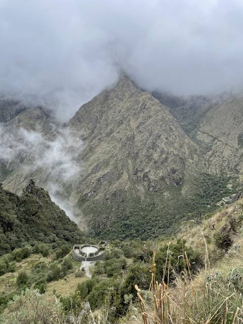 Mountains with cloud cover and old stone structures.