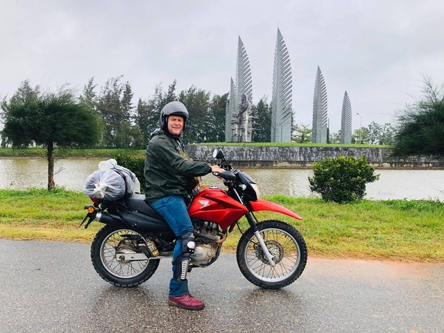 Person riding a motorcycle alongside a water feature.