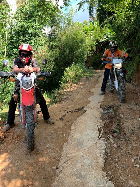Two motorcyclists resting on a dirt trail.