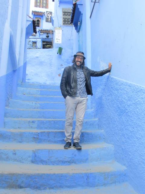       Person standing on blue-painted steps in an alley.
  