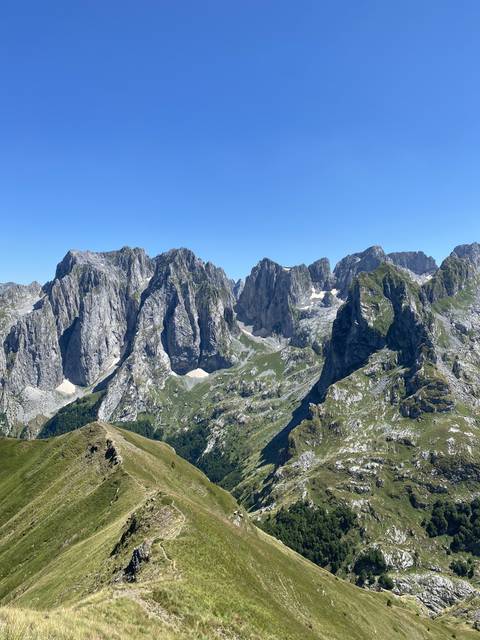 Mountainous landscape with rocky peaks and green valleys.