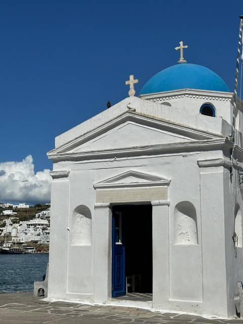 Small white chapel with a blue dome against a blue sky.