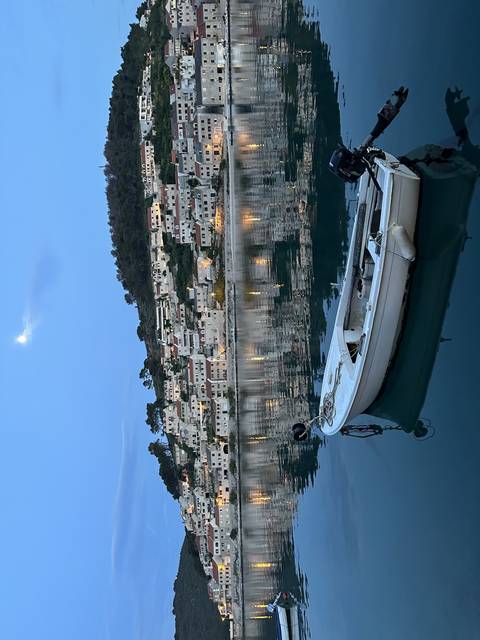 A coastal town at dusk, buildings reflected in the water.