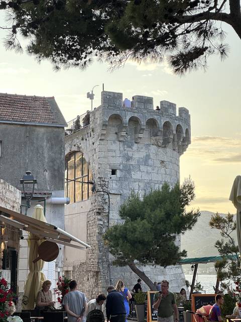       Historic stone structure with people dining outdoors.
  