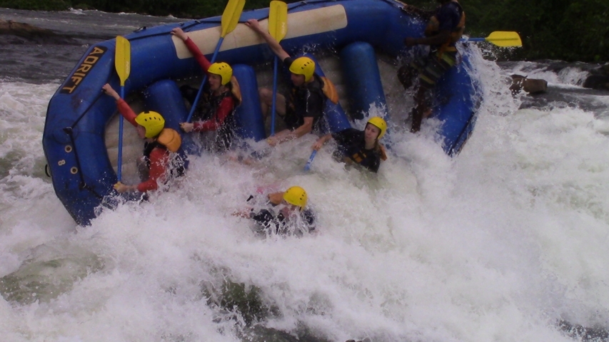 Group of people rafting through whitewater rapids.