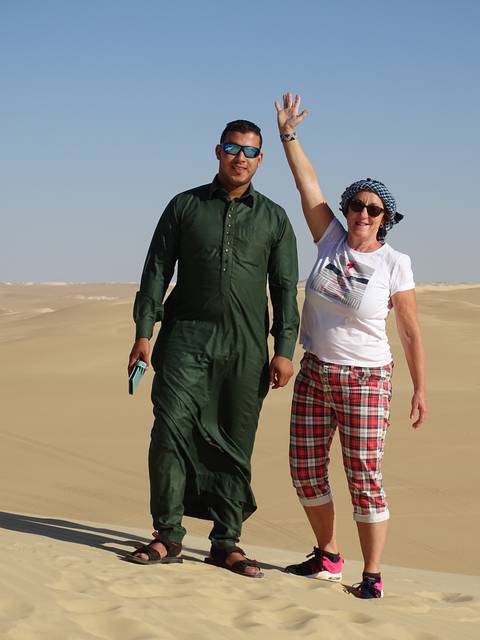       Man and woman posing on a desert landscape.
  