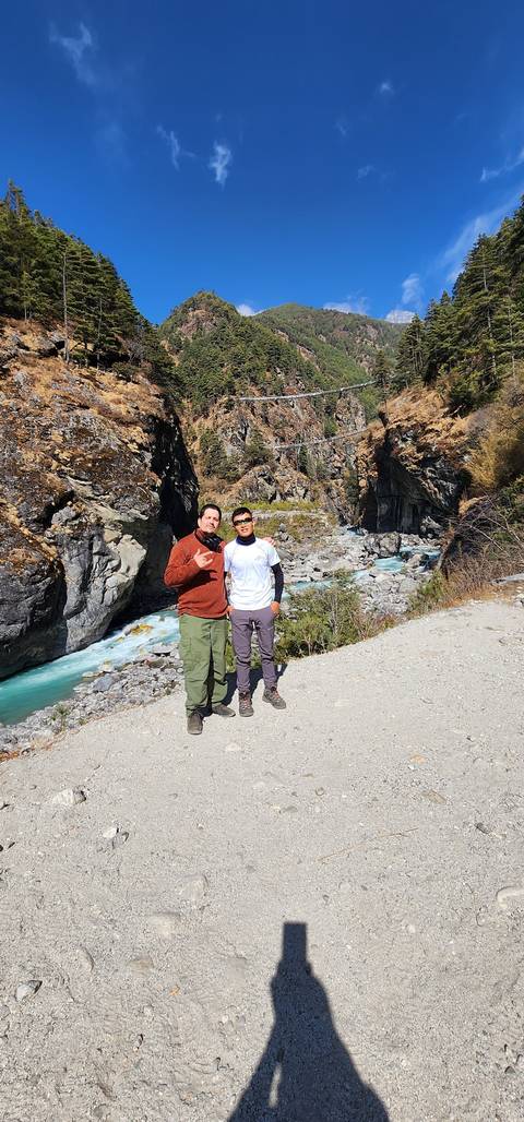 Two people posing by a river in the mountains.