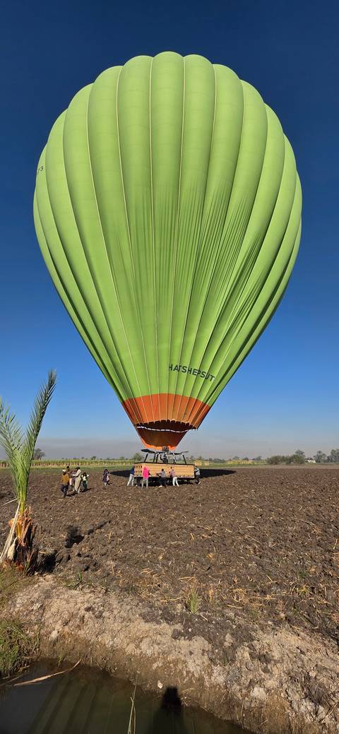 Hot air balloon inflated in a field setting.