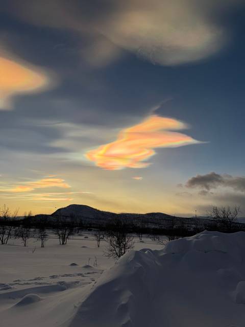 Colorful clouds at sunset over a snowy landscape.