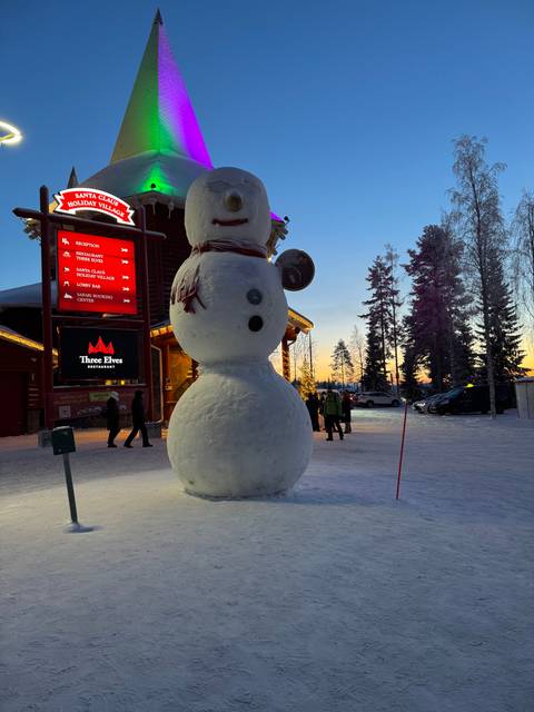 Snowman in an illuminated area during twilight.