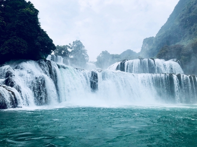       Wide waterfall cascading into a turquoise lagoon.
  