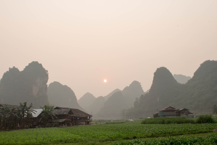       Misty morning view of karst formations and fields.
  