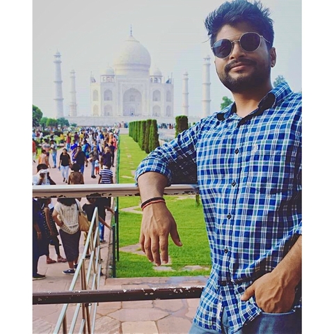 Man standing in front of Taj Mahal with a large crowd in the background.