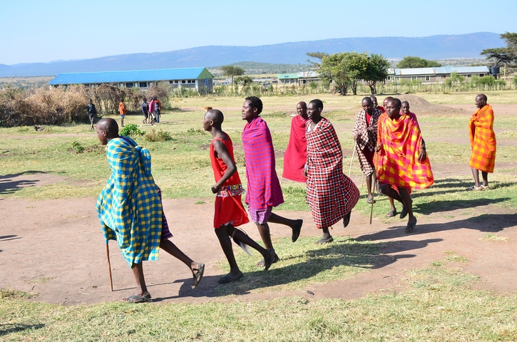 Line of people in traditional clothing walking outdoors.