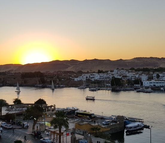 Sunset over a river with boats and buildings.