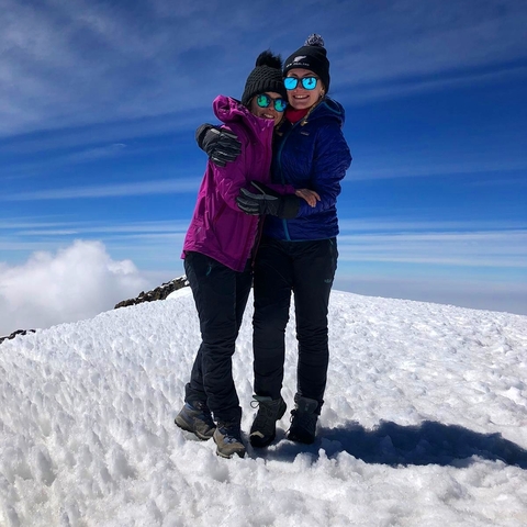 Two people embracing on a snowy mountain peak.
