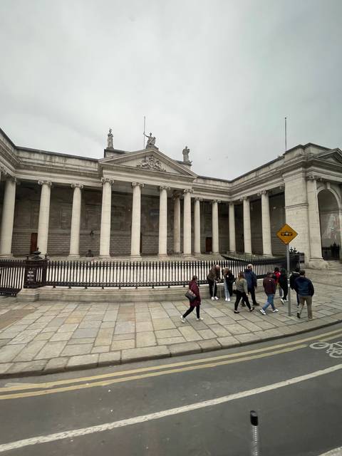 Building with columns and people walking in front.