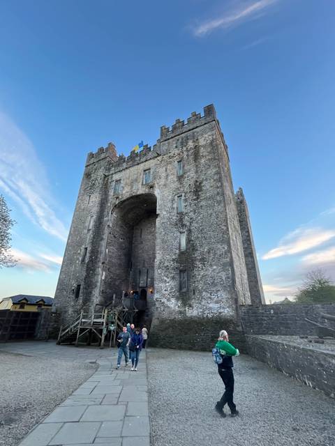       Medieval stone castle with visitors at the entrance.
  