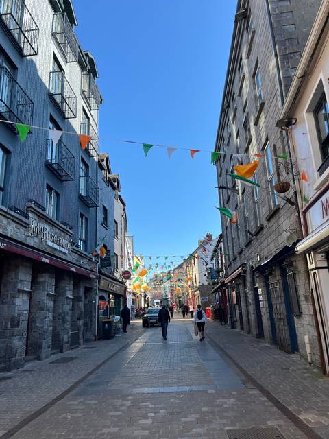 Street with shops and Irish flags hanging overhead.