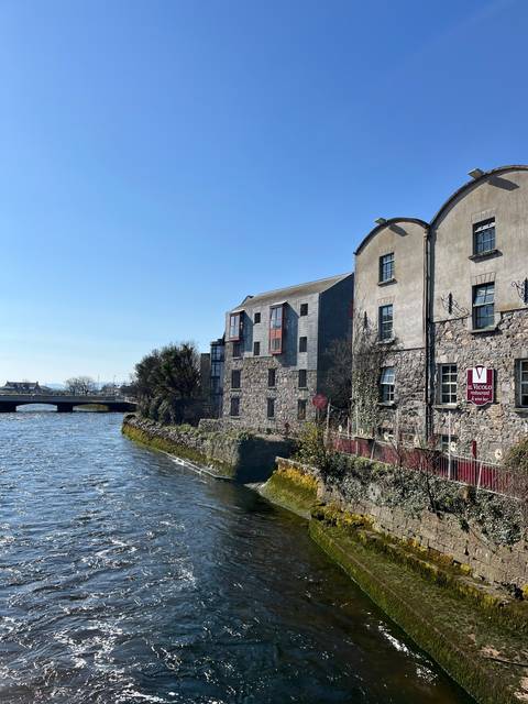 Building by a river with a clear blue sky.