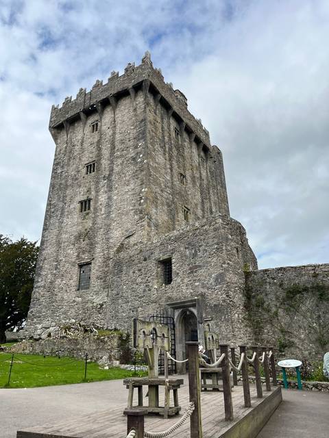 Medieval stone castle with battlements and cloudy sky.