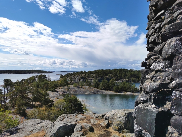 Rocky islands with trees and water under a partly cloudy sky.