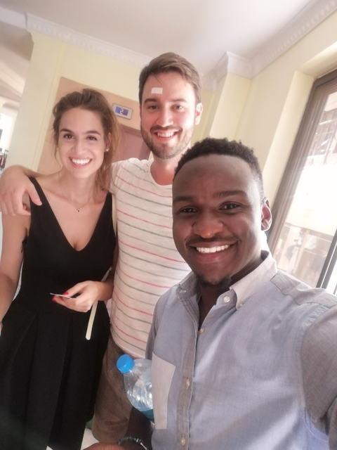 Three smiling people posing for a selfie indoors.