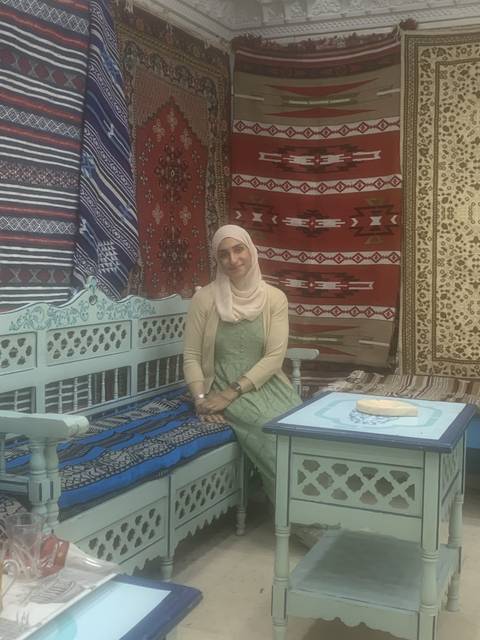       Person sitting in a colorful carpeted room.
  