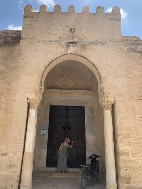       Person standing at a historical building entrance.
  
