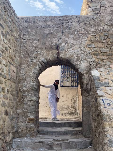       Person standing inside a stone archway.
  