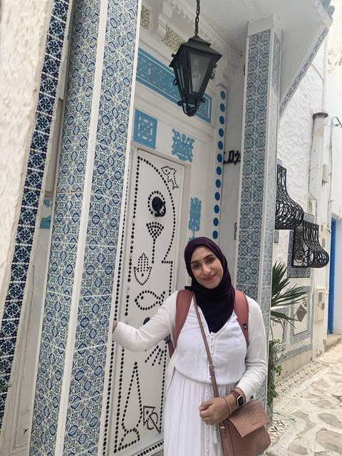       Person standing in front of a blue-tiled entrance.
  