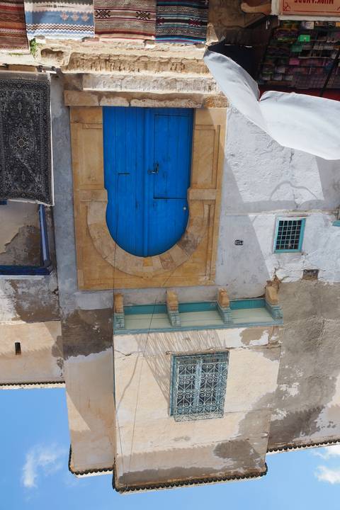       A blue door in a narrow street with colorful walls.
  