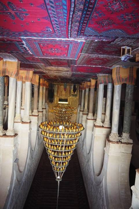       Interior of a mosque with red carpets and chandeliers.
  