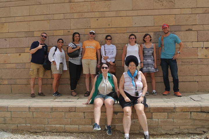A group of people posing in front of a stone wall.