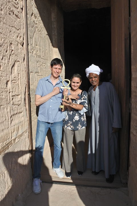 Couple posing with a local man, one holding an ankh.