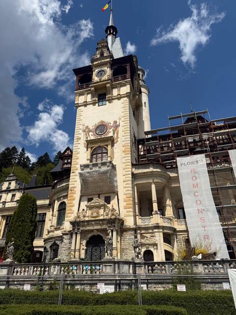 Peles Castle in the sunlight with blue skies.
