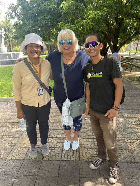 Three people standing on a tiled path outside.